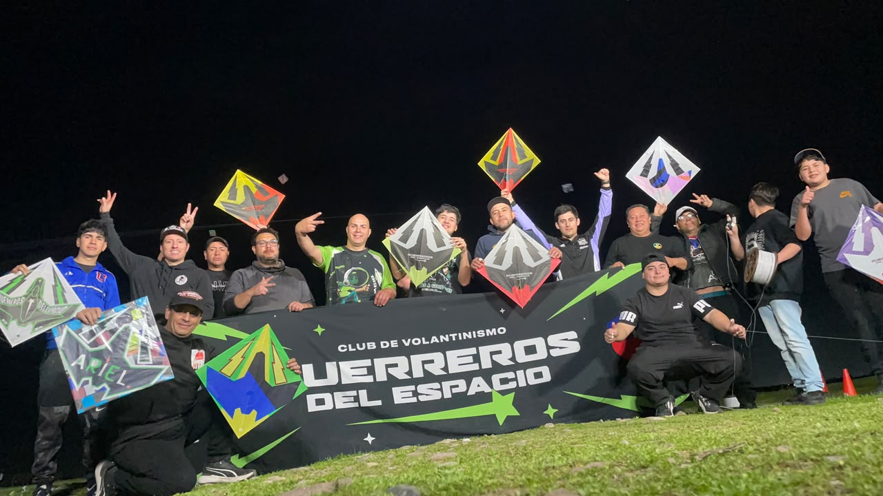 Integrantes celebrando juntos con sus volantines en una fotografía nocturna